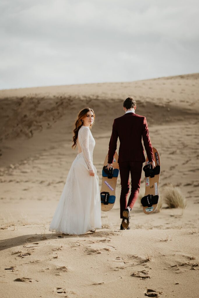 Bride and groom walking across the sand dunes in Oregon for their adventure elopement