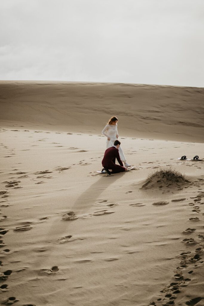 Bride and groom stepping into sand boards during their adventure elopement in Oregon