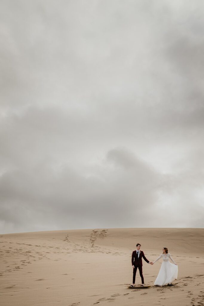 Bride and groom sand board together during their Oregon sand dunes elopement