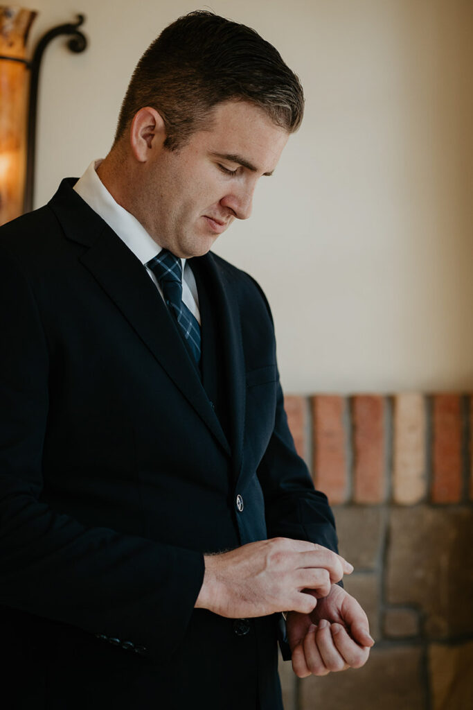The groom adjusting his suit sleeve. 