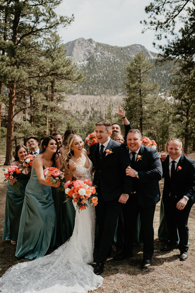 The bride, groom, bridesmaids, and groomsman laughing and dancing in the forest. 