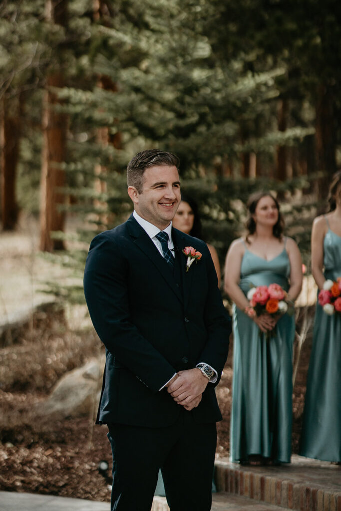 The groom smiling with bridesmaids in the background.