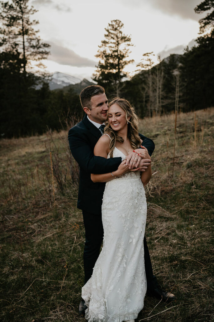 The bride and groom hugging while standing in the forest in Estes Park. 