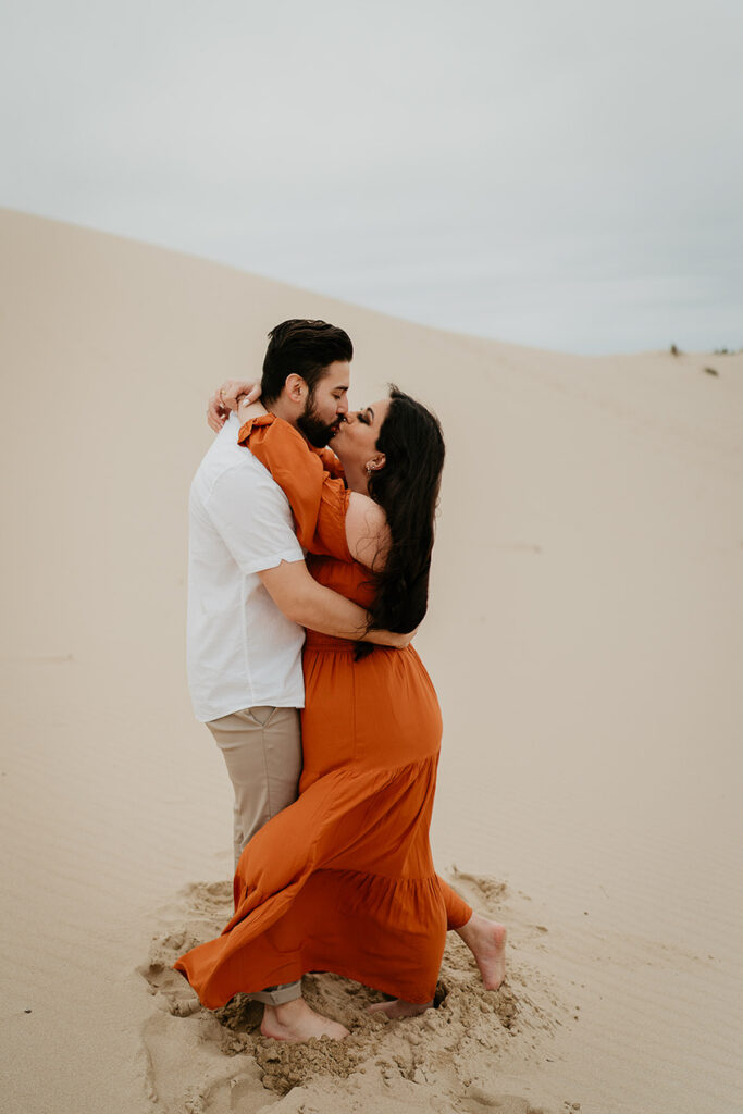 A couple kissing while barefoot on Oregon Coast Sand Dunes. 