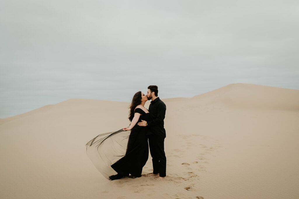 A couple kissing on top of sand dunes. 