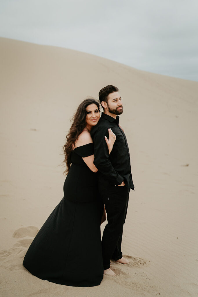 A fiance holding her boyfriend during their Oregon Coast Sand Dune Engagement session. 