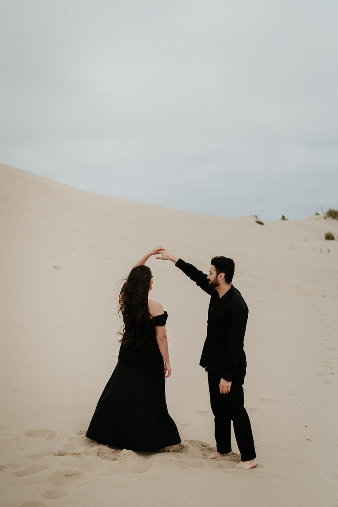 A couple dressed in all black dancing on Sand Dunes. 