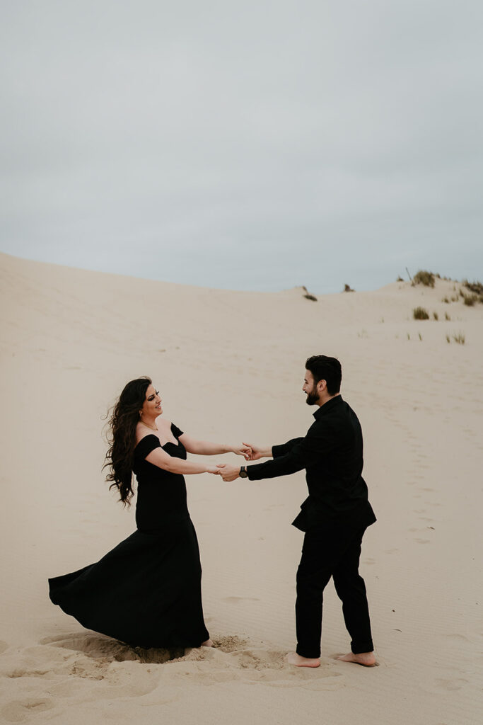 A couple dressed in all black dancing on Sand Dunes. 