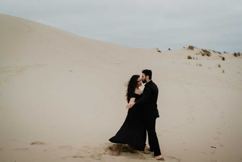 A couple dancing on Oregon Coast Sand Dunes during their engagement session. 
