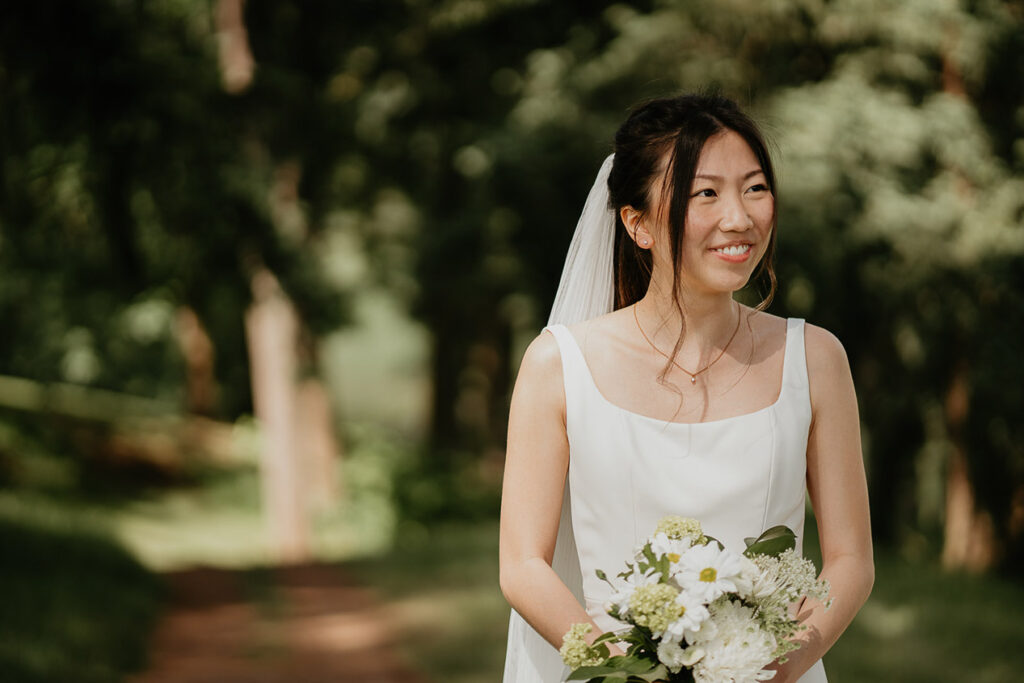Judith smiling and holding a bouquet of flowers before her wedding. 