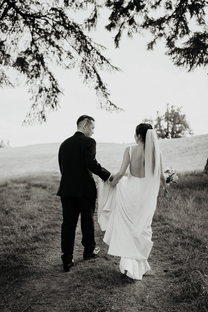 A black and white photo of Judith and Joshua walking along a grassy trail at Oregon Golf Club. 