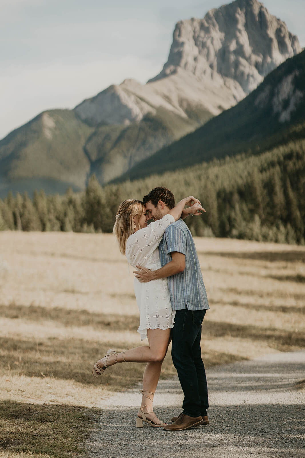 A couple dancing with pine trees and mountains in the background.
