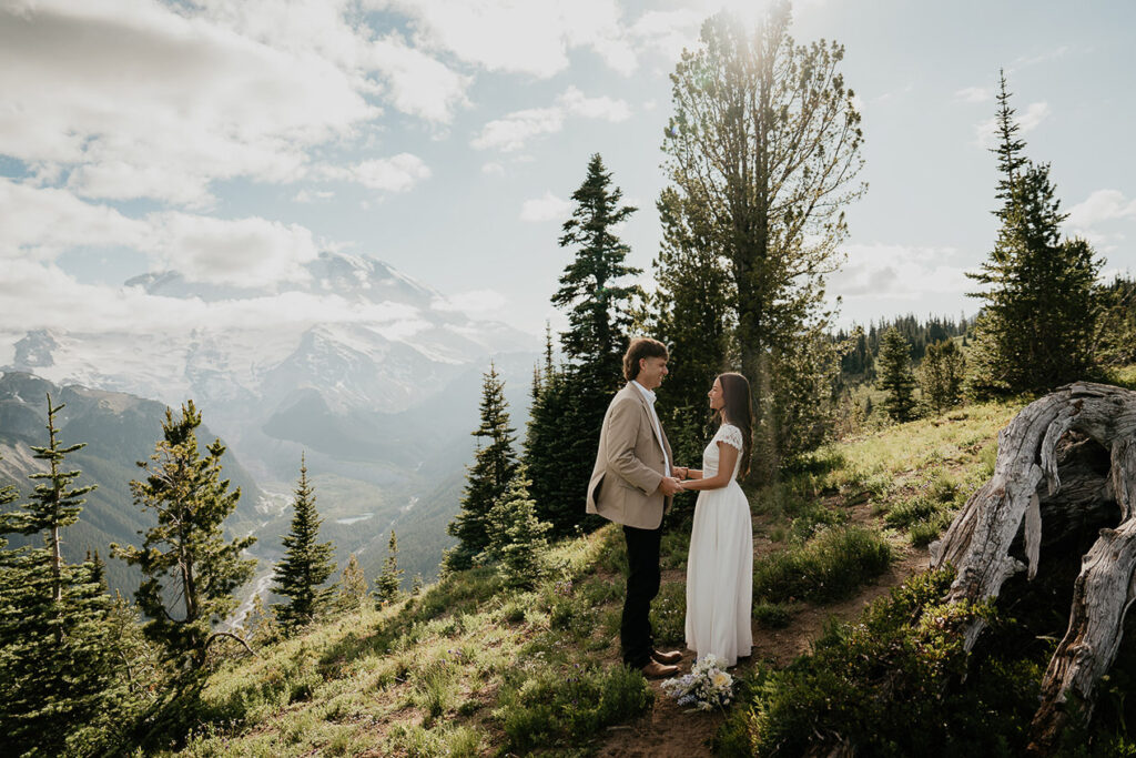 The couple holding hands on a trail with Mt Rainier in the background. 