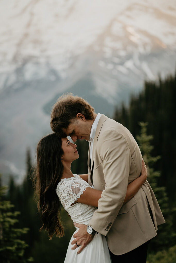 The husband and wife hugging with Mt Rainier in the background.