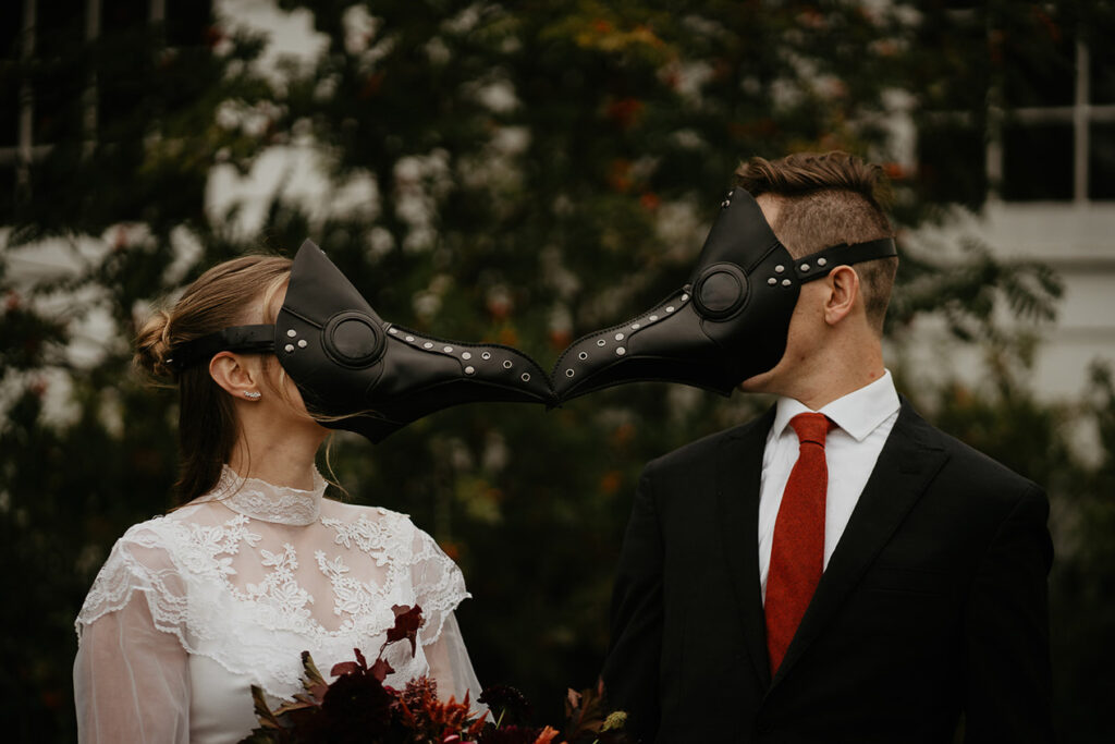 A couple wearing bird masks facing each other.