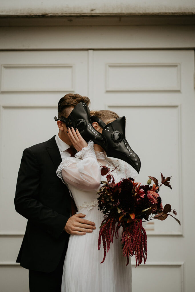 A couple in bird masks embracing each other. 