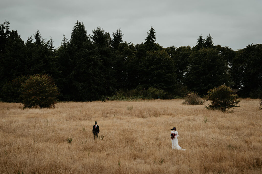 A couple wearing bird masks standing in an open field. 