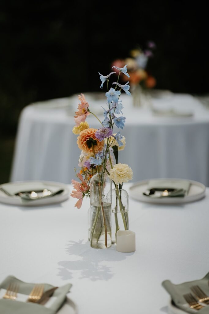 Colorful summer wedding flowers in a bud vase on reception tables