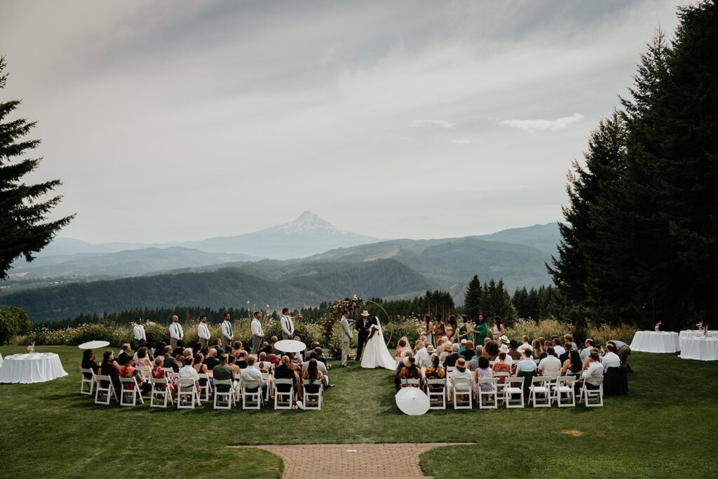 Bride and groom stand at their outdoor wedding ceremony overlooking Mt Hood 