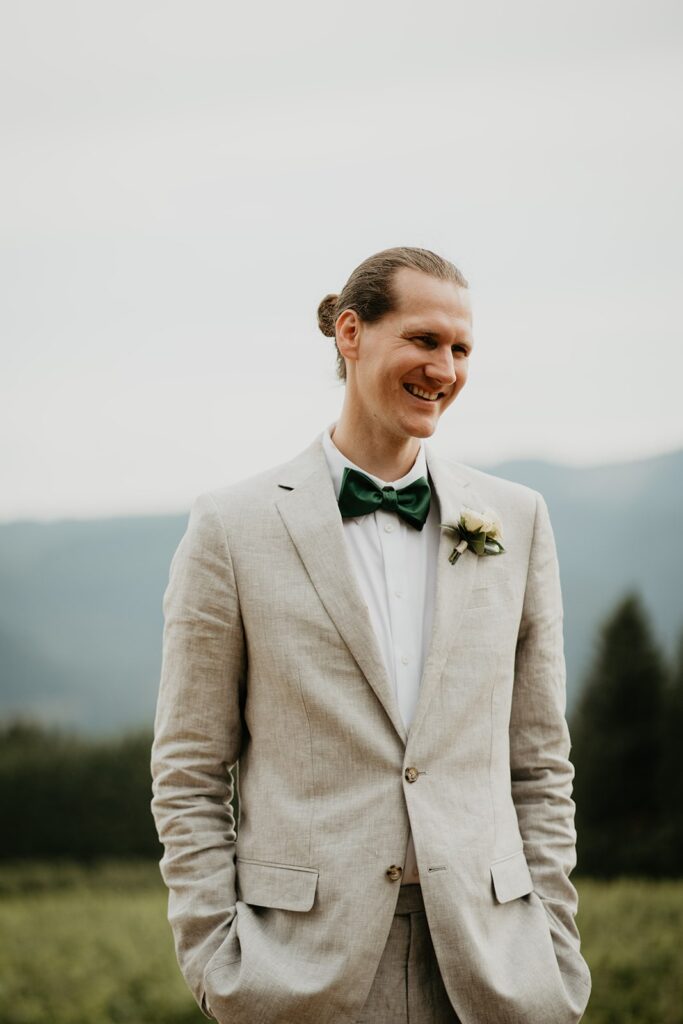 Groom wearing gray linen suit and green bowtie during winery wedding in Washington