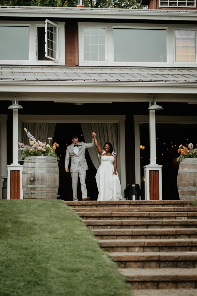 Bride and groom cheer as they enter their winery wedding cocktail hour with guests