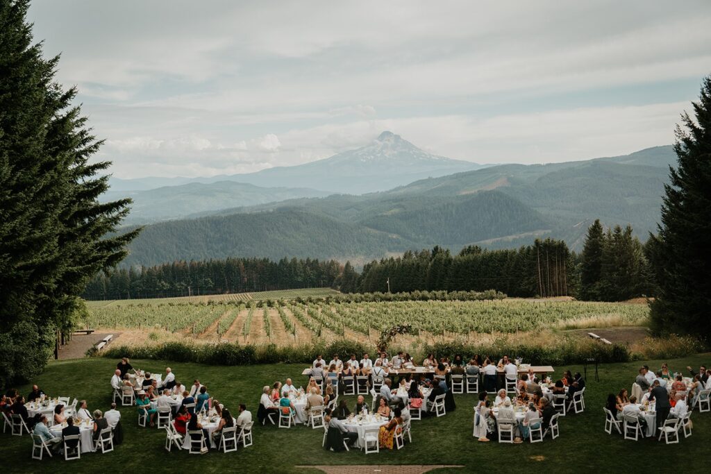 Guests sit at tables during the outdoor wedding reception at Gorge Crest Vineyards