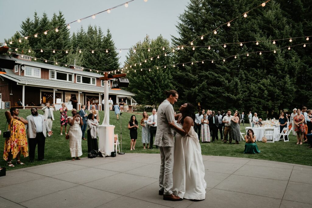 Bride and groom first dance under string lights at outdoor wedding reception