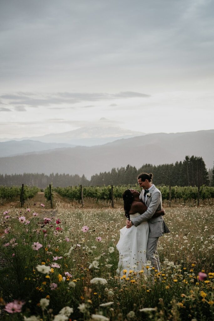 Bride and groom stand in a wildflower field during couple photos at Gorge Crest Vineyards wedding
