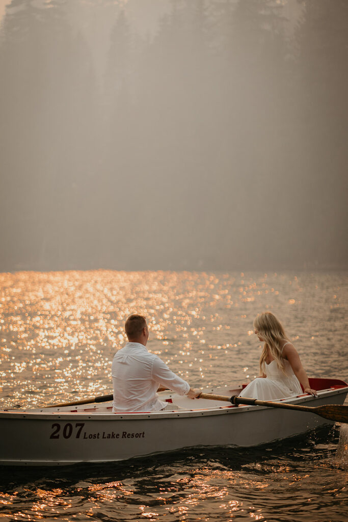 The groom-to-be rowing a boat with his fiancé as on the smokey Lost Lake. 