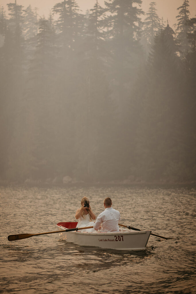 The groom-to-be rowing a boat with his fiancé as on the smokey Lost Lake. 