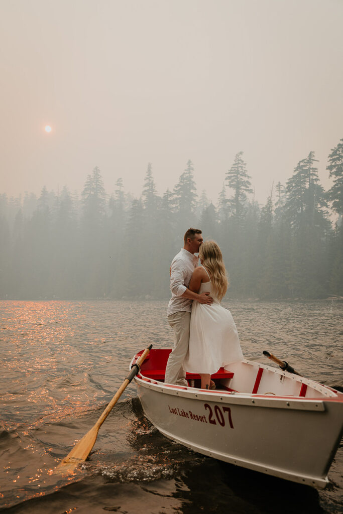 A couple kissing while standing on a row boat in Lost Lake. 
