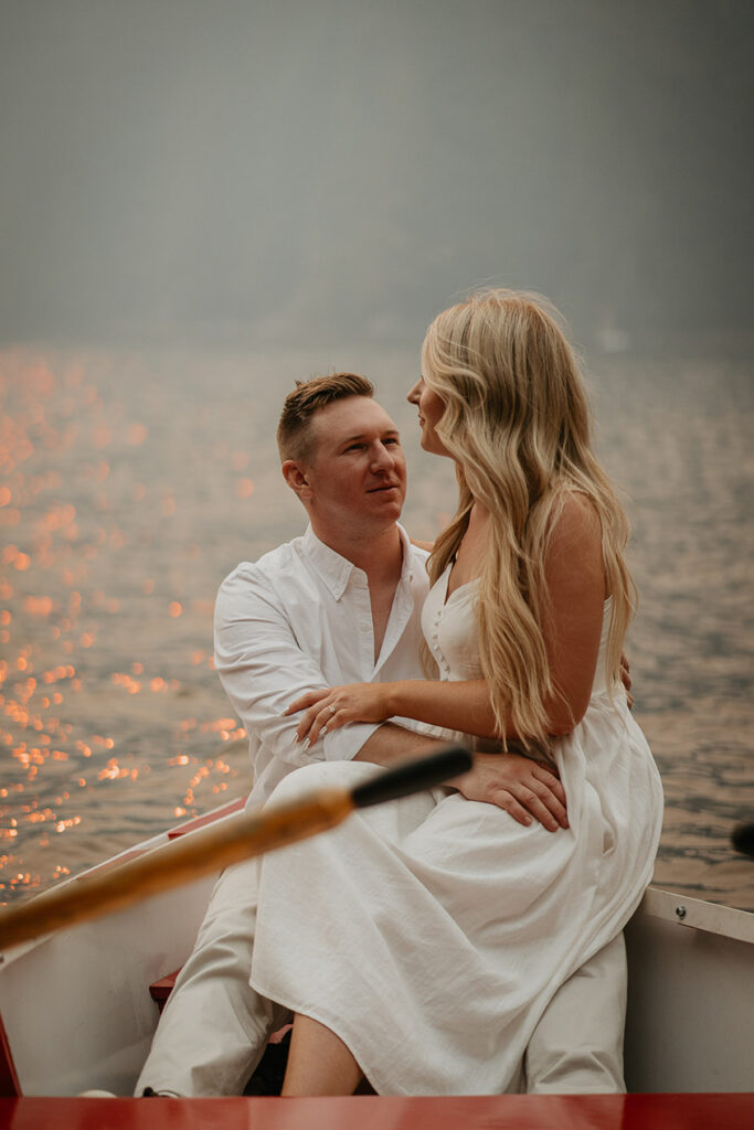 A fiance sitting on her future groom's lap while on a row boat. 