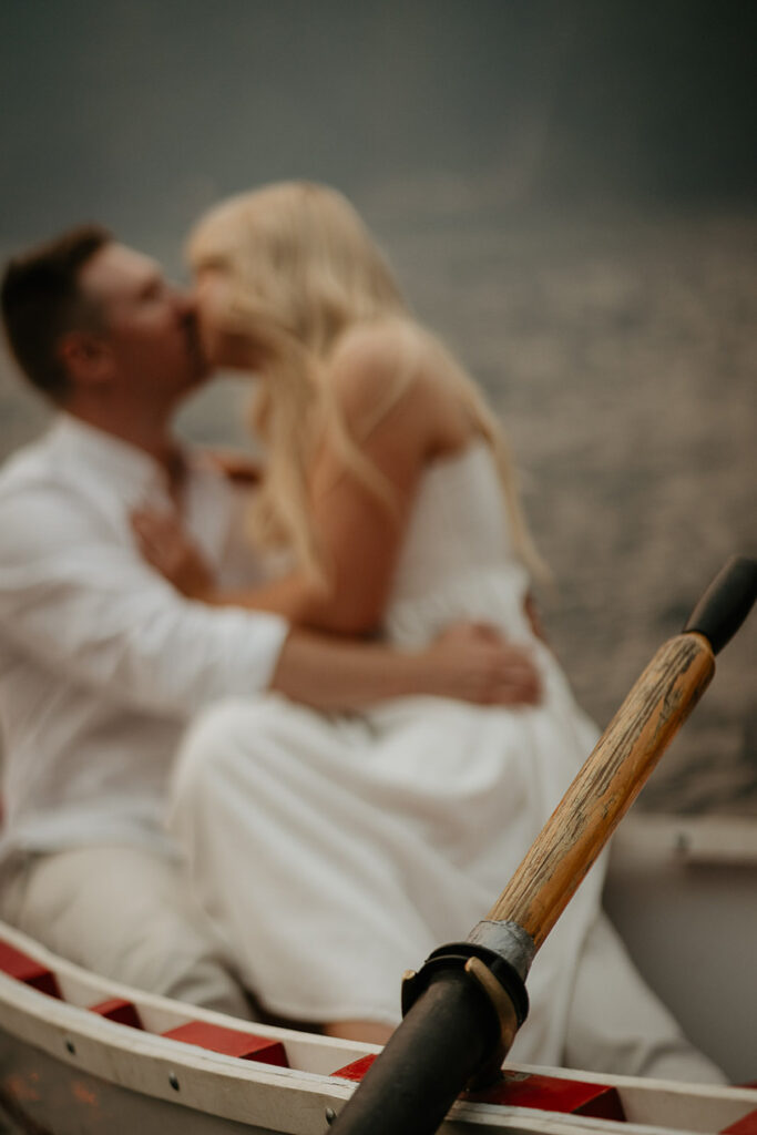 A row boat oar, with a blurry image of a couple kissing in the background. 