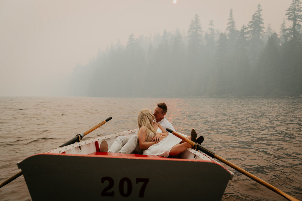 A couple kissing in a row boat on Lost Lake while smoke fills the air. 