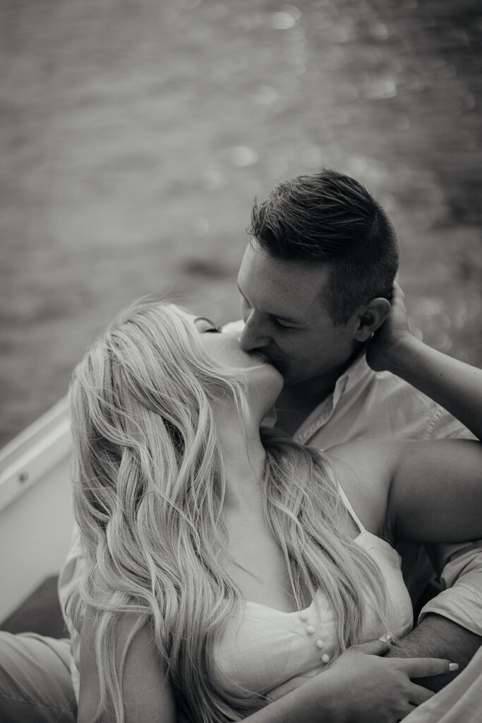 A couple kissing on a row boat. 
