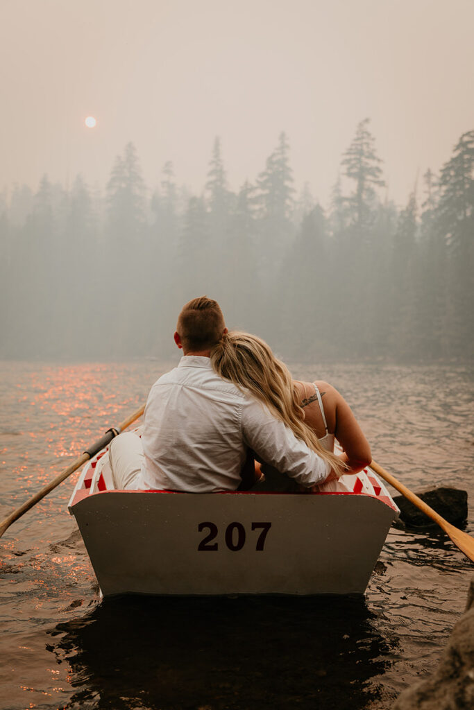 A couple holding each other while looking out over the smokey water. 