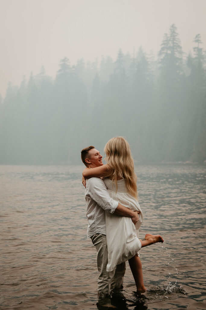 The couple hugging each other while standing in a lake. 