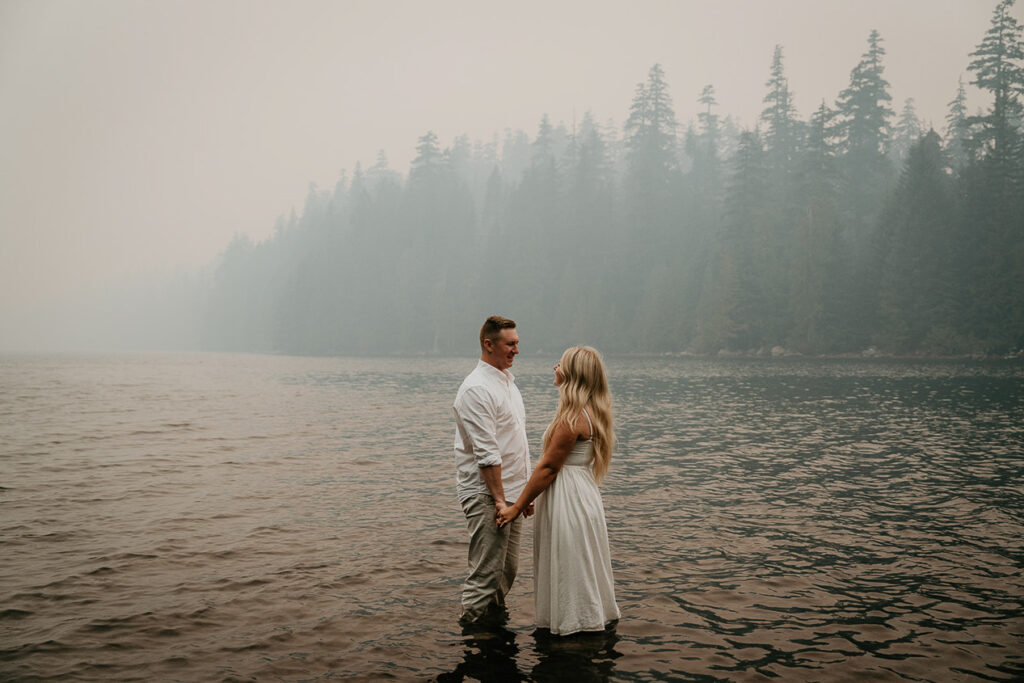 The couple holding hands while standing in the lake. 