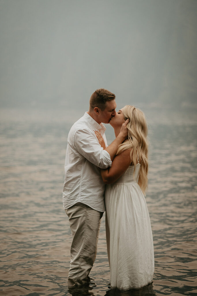 The couple kissing while standing in Lost Lake. 