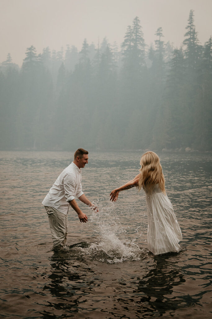 The couple splashing water on each other standing in Lost Lake. 