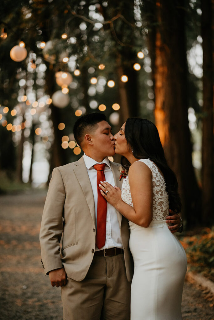 The couple kissing under twinkly lights. 