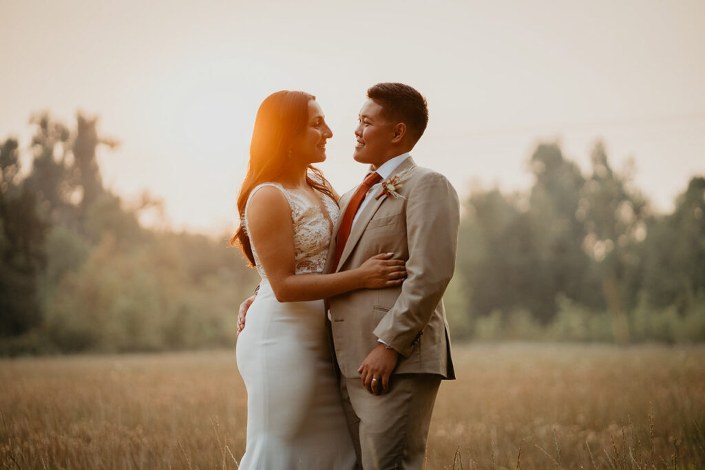 The couple holding each other in a golden field. 