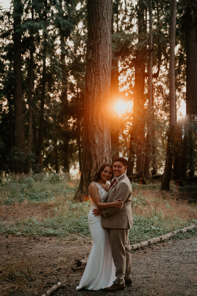 The couple hugging in a pine forest as the sun sets. 