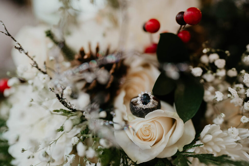 A ring sitting on a rose with mistletoe in the background. 
