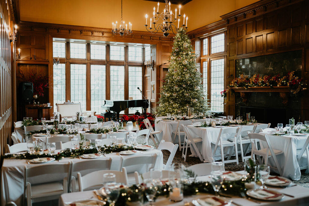 Decorated dinner tables with a Christmas tree and piano in the background. 