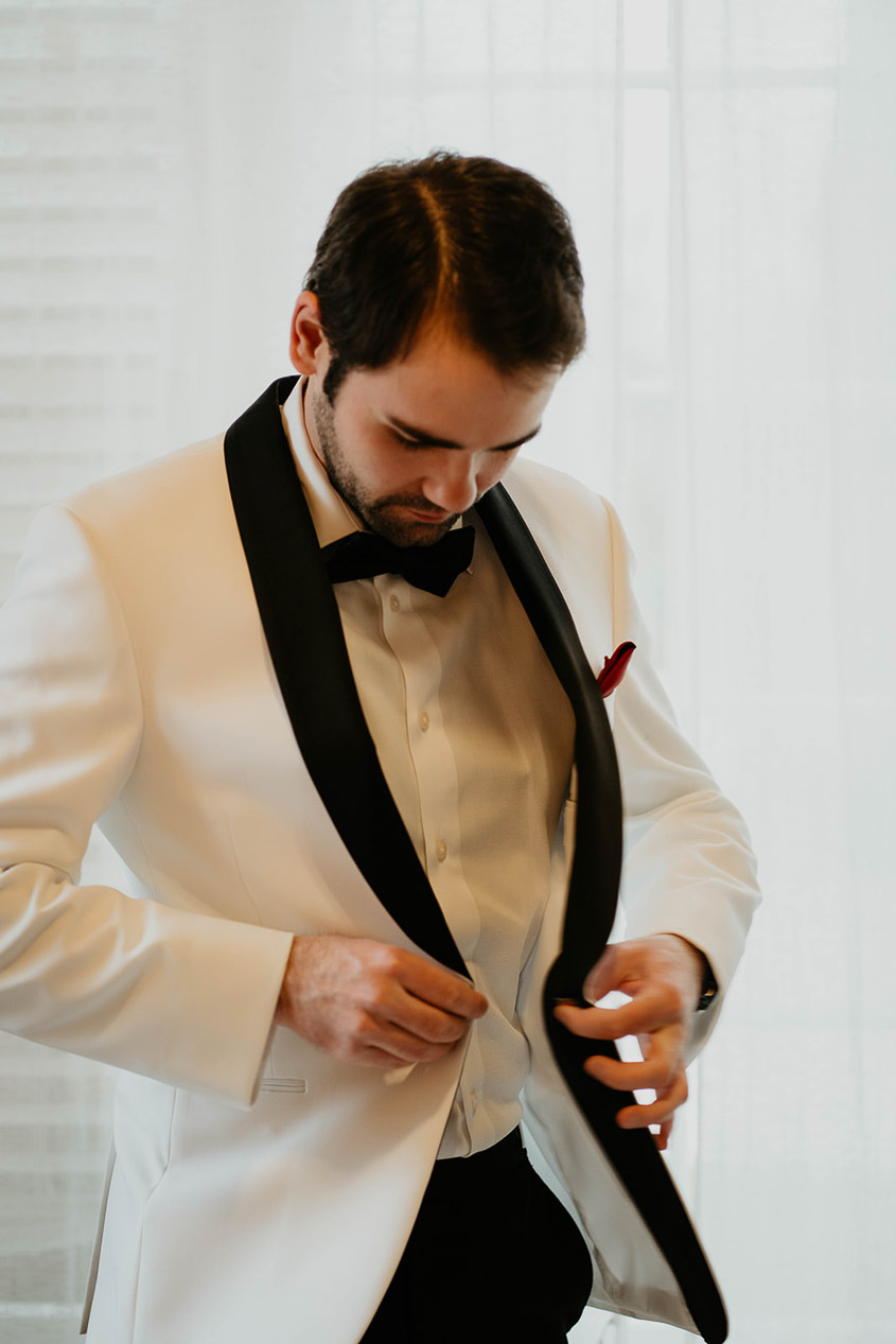 The groom buttoning up his jacket.