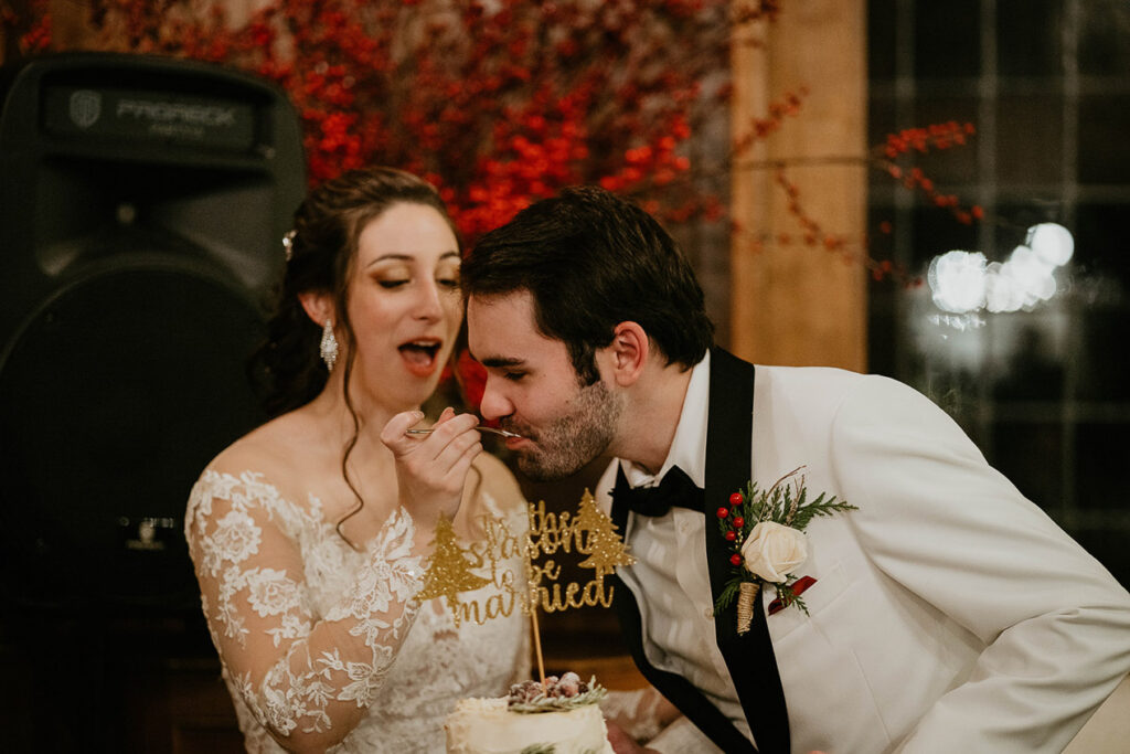 The bride feeding the groom a piece of their wedding cake. 