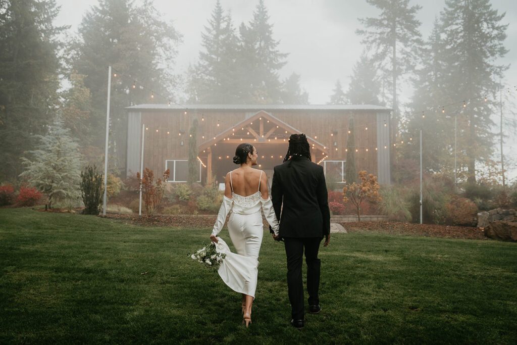 The bride and groom holding hands, walking through the mist on Rocky Hill Weddings & Events's grassy field. 