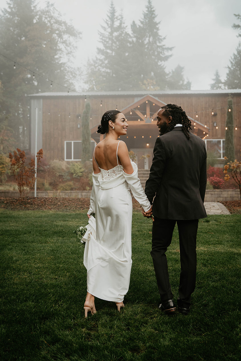 The bride and groom holding hands, walking through the mist on Rocky Hill Weddings & Events's grassy field. 
