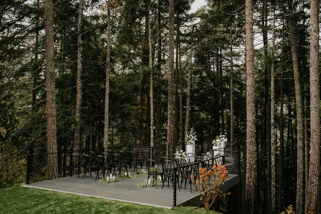 Rocky Hill Weddings & Events' ceremony space, with black chairs and a forested background. 